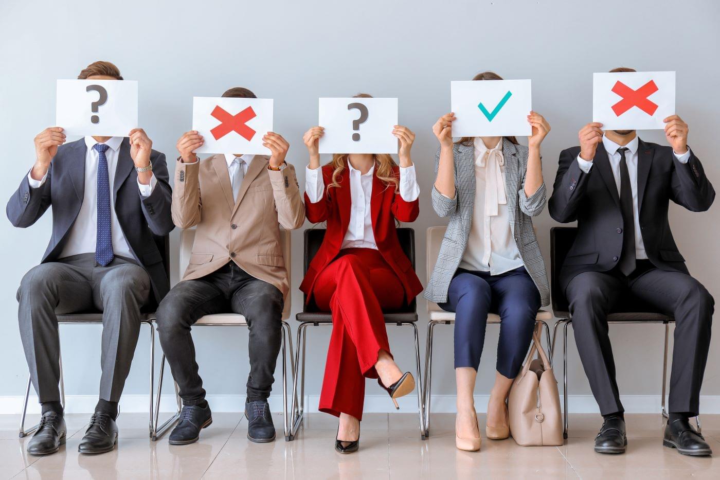 People Lined Up in Chairs with X's, Check Marks, or Question Marks Over Their Face