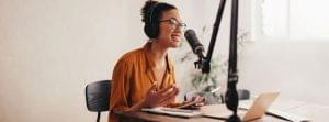 Woman sitting in front of a podcasting microphone for an internal podcast.