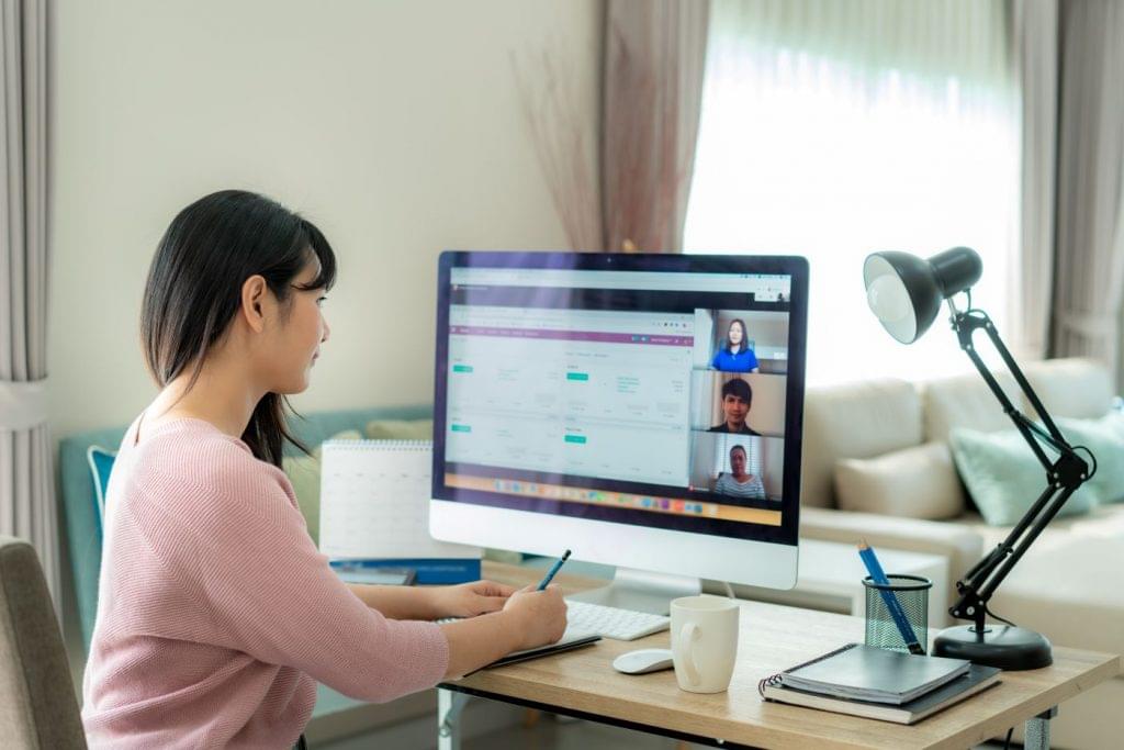 Woman working remotely and video conferencing her coworkers.