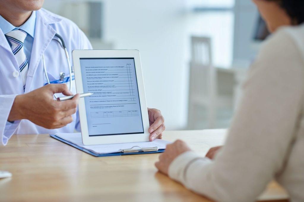 Doctor providing a patient with a questionnaire on a tablet.