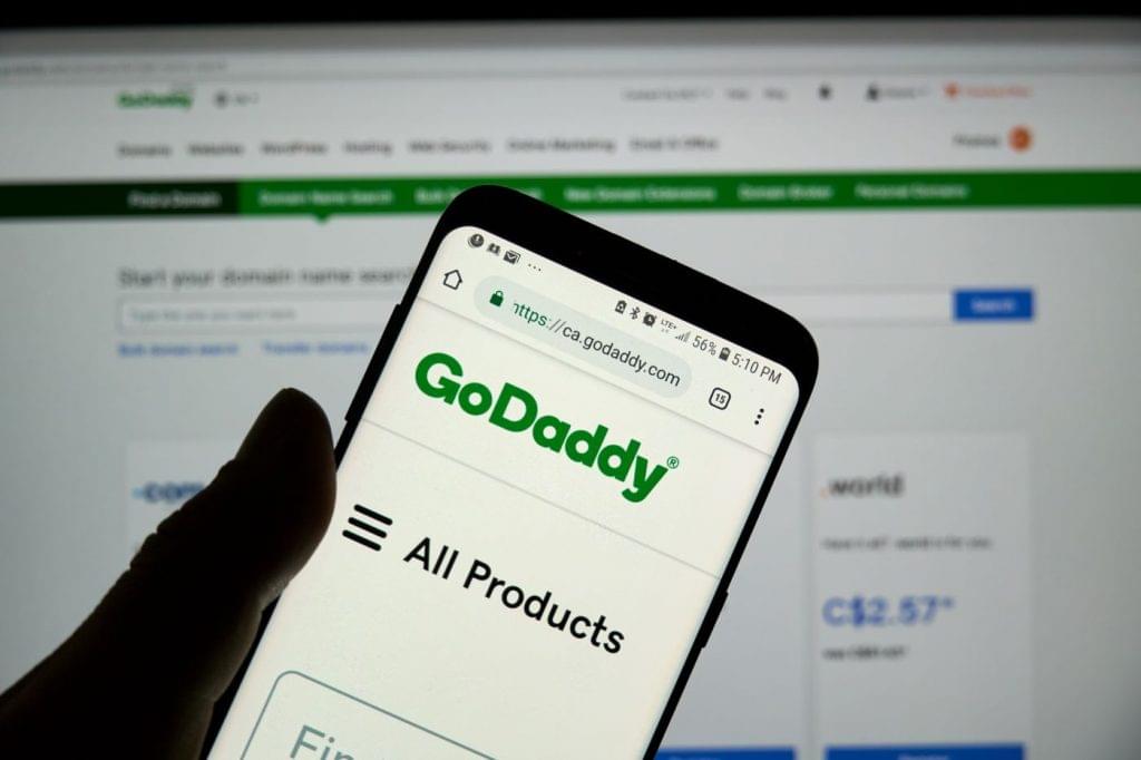 The GoDaddy site on a mobile phone held up in front of the same site on desktop.