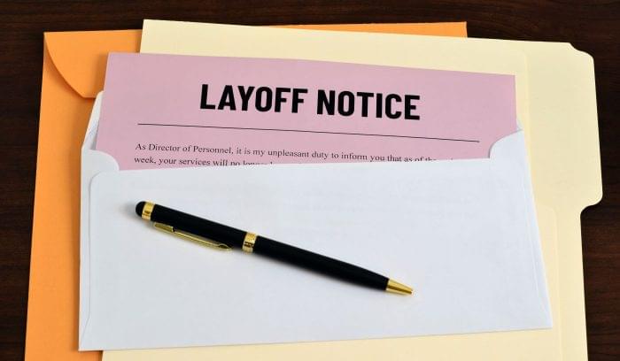 Layoff pink slip in an envelope with a pen on top.