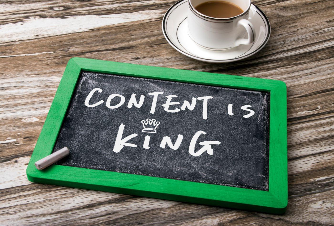 Blackboard with "content is king" written on it next to a cup of coffee.