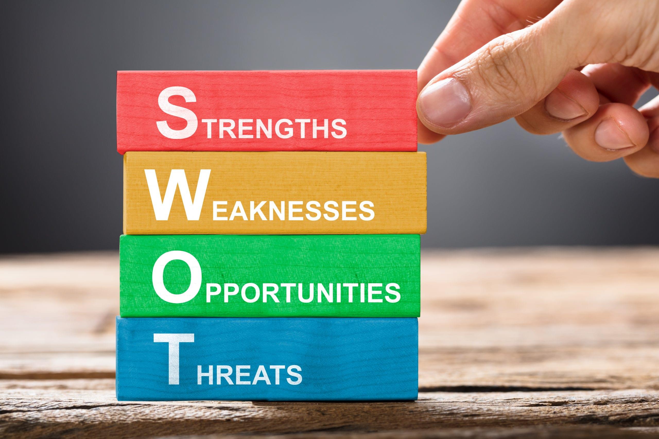 Closeup of hand building colorful SWOT concept with wooden blocks on wood
