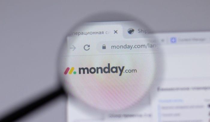 A magnifying glass zooms in on the monday.com logo displayed on a webpage.