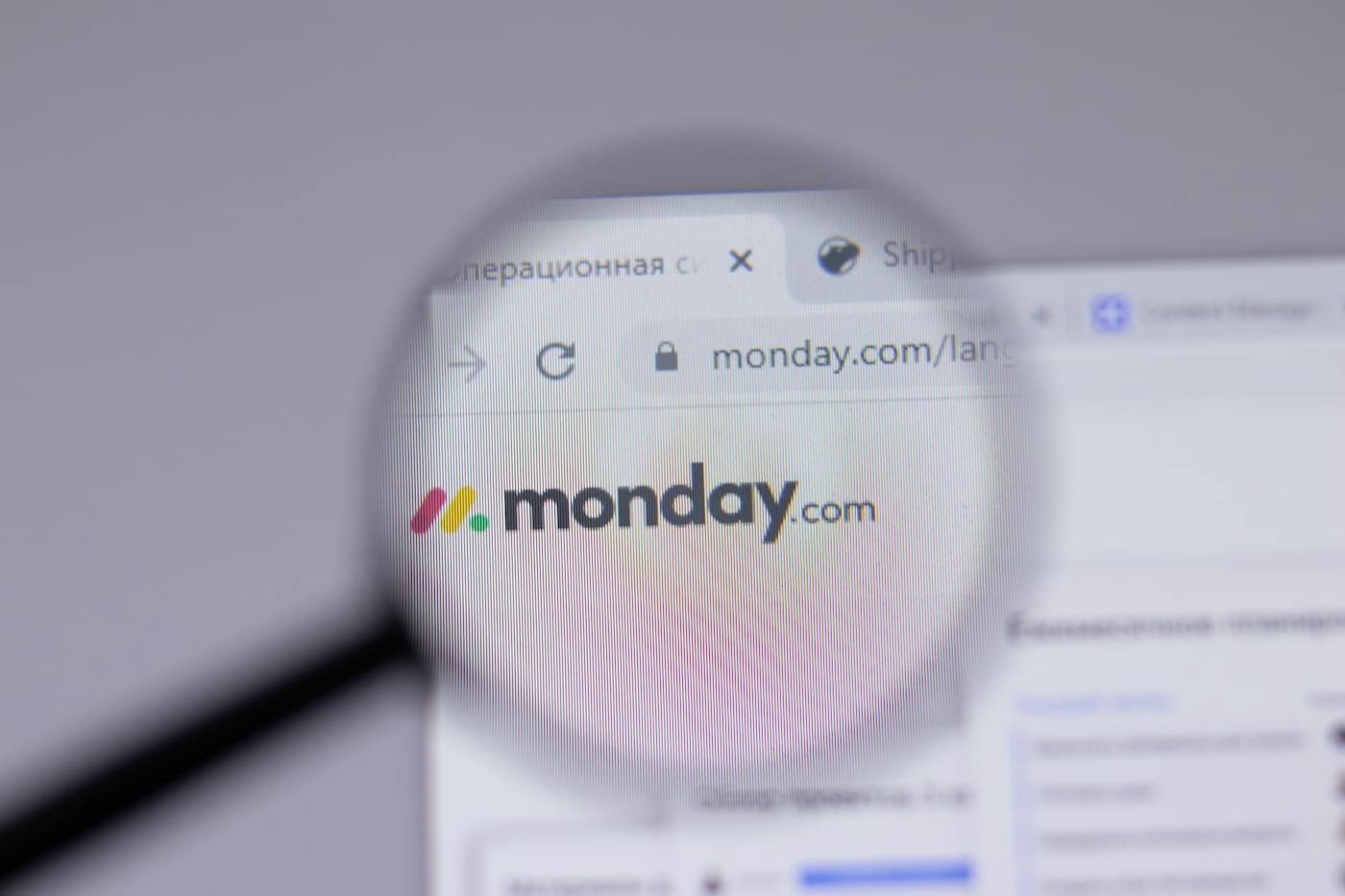 A magnifying glass zooms in on the monday.com logo displayed on a webpage.