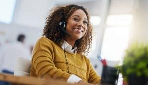 A happy woman listening to a call through a VoIP headset.