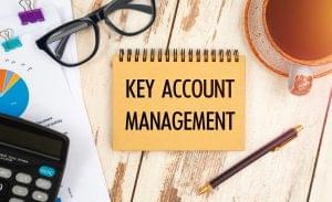 KEY ACCOUNT MANAGEMENT is written on a notepad on an office desk with office accessories.